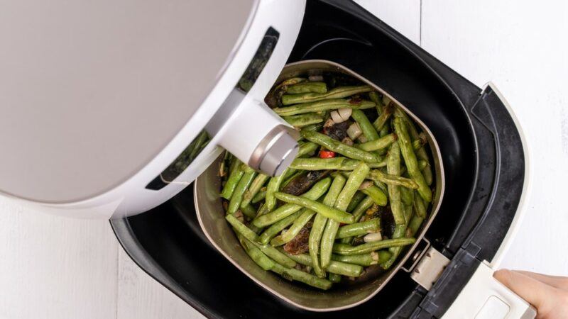 An air fryer containing green beans