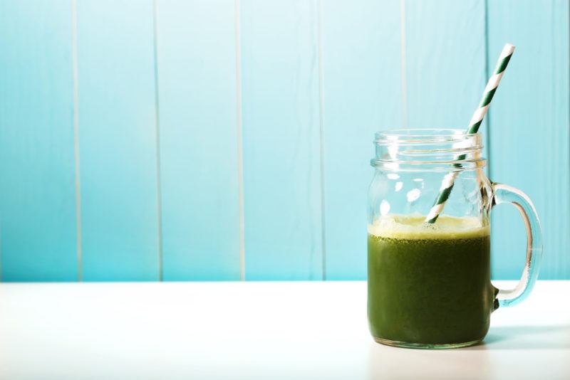 A glass of green juice against a blue background