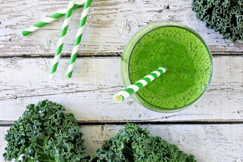 Green juice on a table with kale and straws