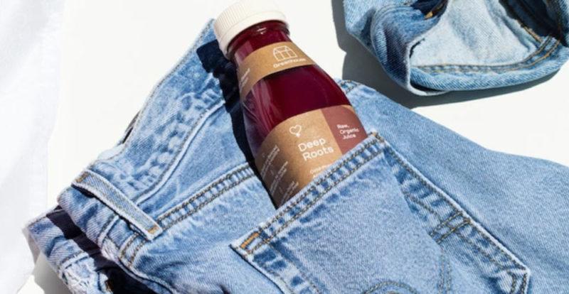 A Deep Roots bottle of juice from Greenhouse Juices in the pocket of a pair of jeans