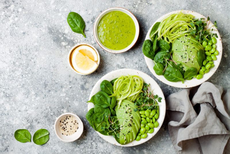 Two white bowls with different green ingredients