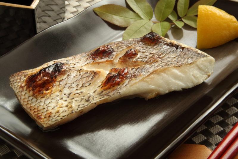 A black plate with grilled fish