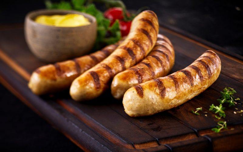 Grilled sausages | Food For Net Four grilled sausages on a wooden board next to mustard
