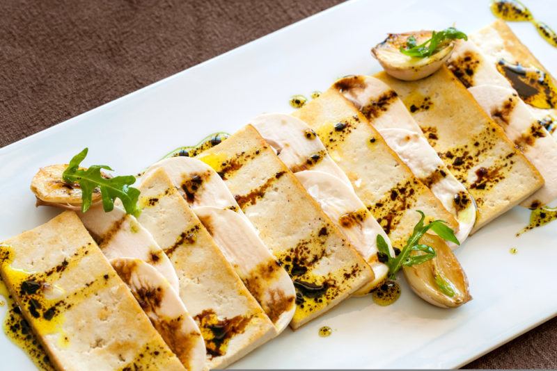 A white plate with tofu that has been grilled on a BBQ