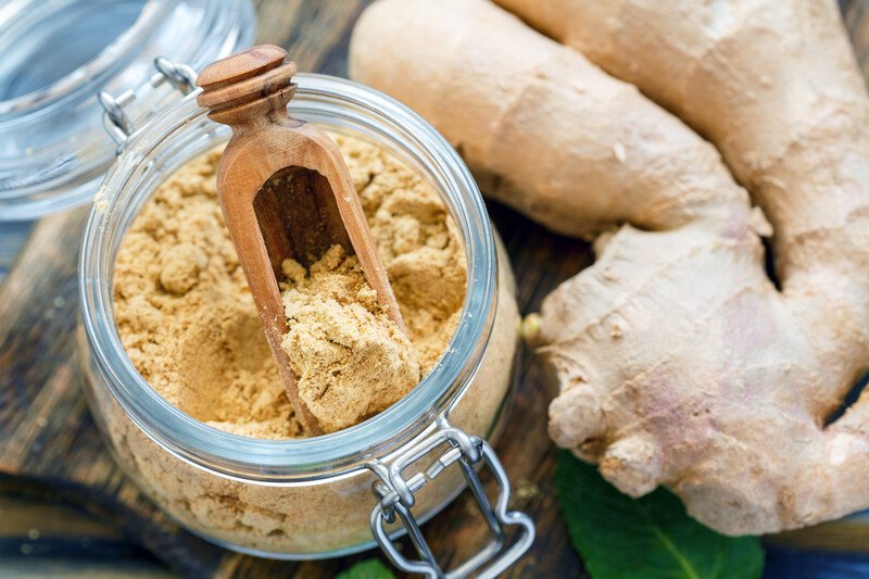 top view image of ground ginger in a glass jar with fresh ginger beside it