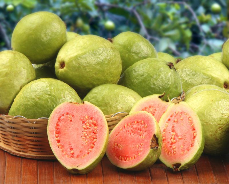 A selection of fresh guava on a table, with some sliced open