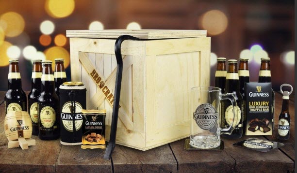 Guinness Lover’s BroCrate | Food For Net A pale wooden box on a wooden table, surrounded by Guinness bottles and related products.