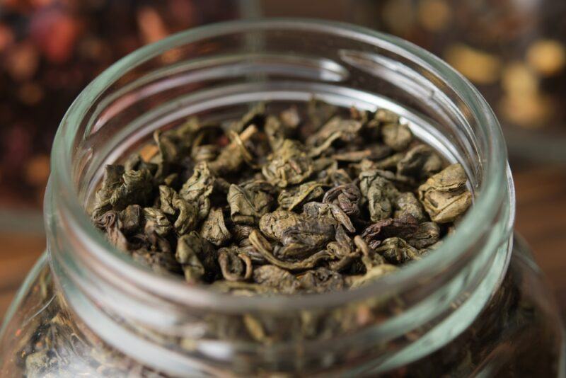 closeup image of a glass jar with loose gunpowder tea