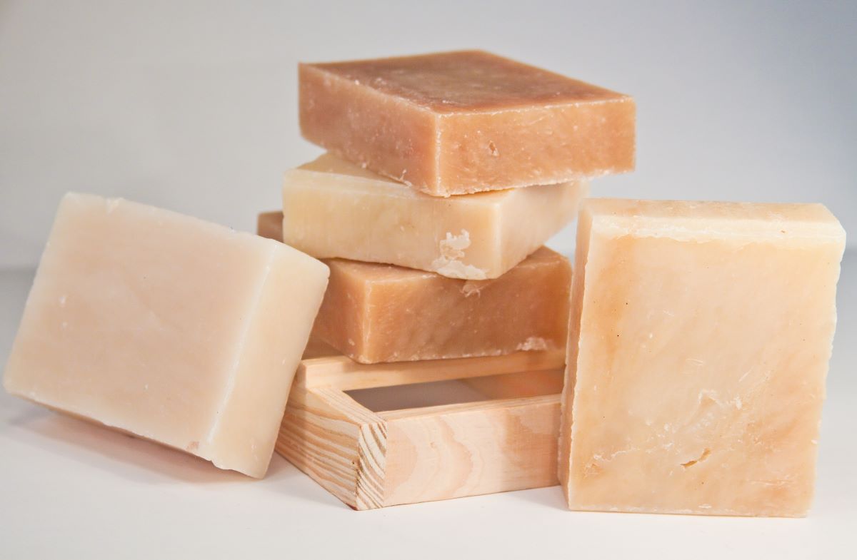 5 tan hand-crafted soaps sitting on a natural wood soap holder