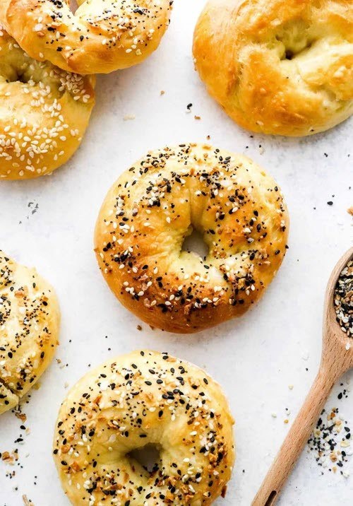 Various healthy air fryer bagels on a white background, topped with seeds