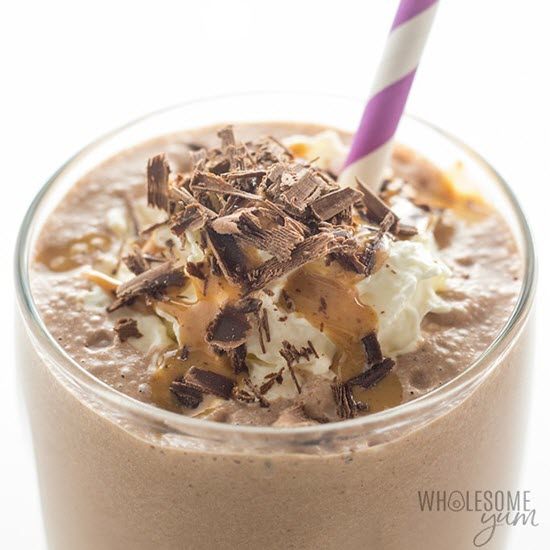 A chocolate smoothie in a glass with a chocolate, caramel and cream topping. 