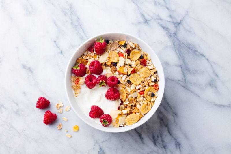 A white bowl of cereal and fruit