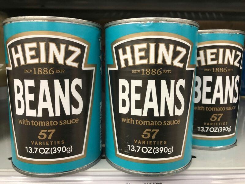 Three cans of Heinz beans on a store shelf