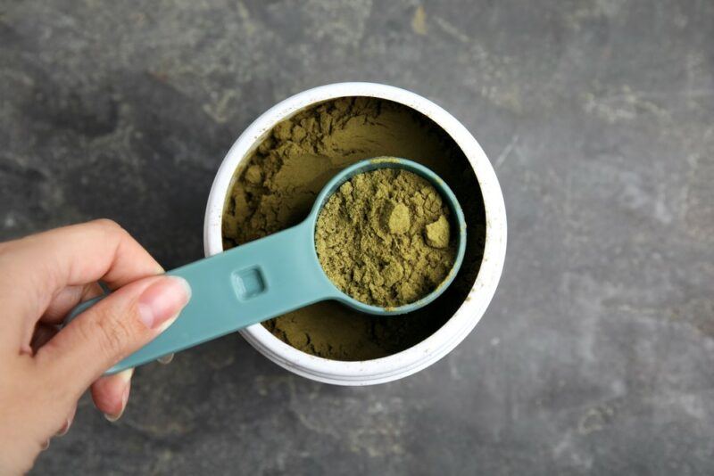 Someone scooping hemp powder to make a protein shake