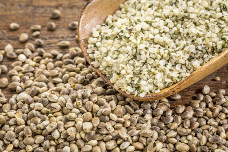 Hemp seeds on a table, with a scoop of hemp hearts on the top