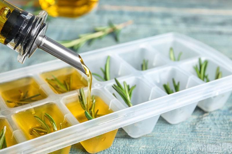 Adding olive oil and rosemary to an ice cube tray