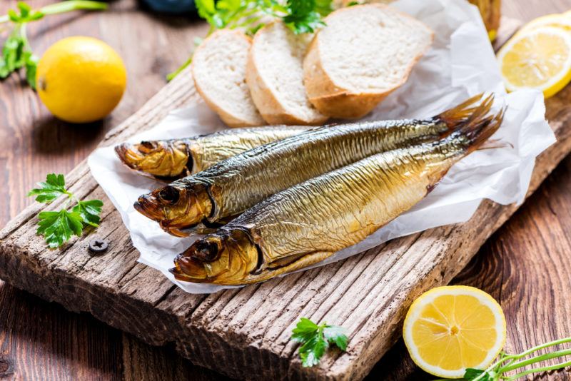 Three herrings on some paper and a wooden board