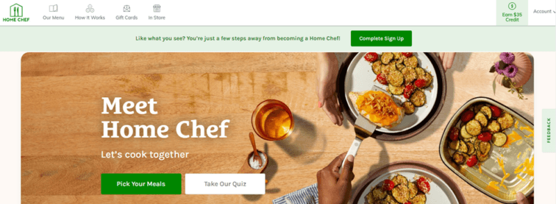 A website from Home Chef, showing a wooden table with a variety of different types of meal, plus a glass of wine