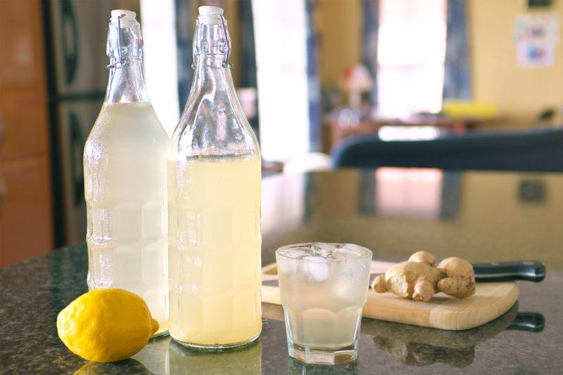 Two glass bottles and a glass containing homemade ginger beer