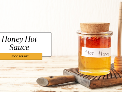 A jar of honey hot sauce with the label hot honey, next to a honey stirrer and a hot pepper