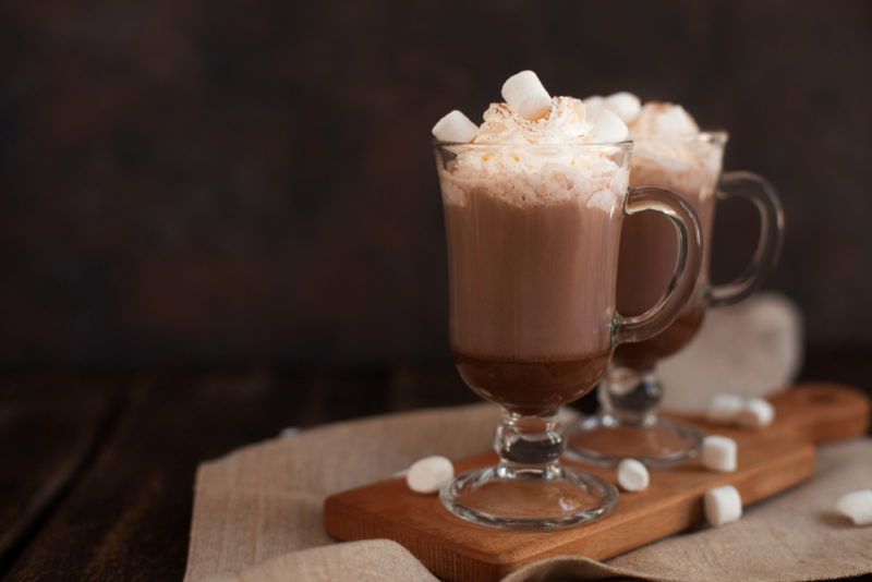 Two glass mugs containing hot chocolate with cream and mashmallows