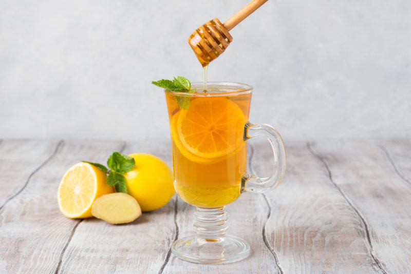 A glass mug containing lemon and honey with water