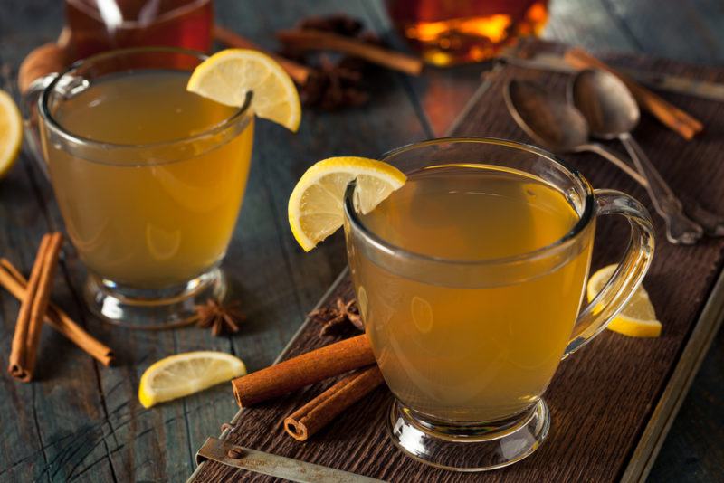 Two glass mugs of hot toddy with lemon and spices