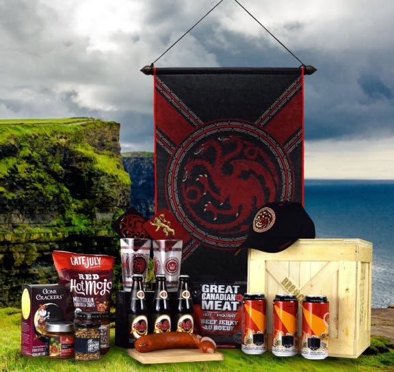 An outdoors image showing a House Targaryen banner, a hat, a crate, coasters and glasses, along with beer and snacks.