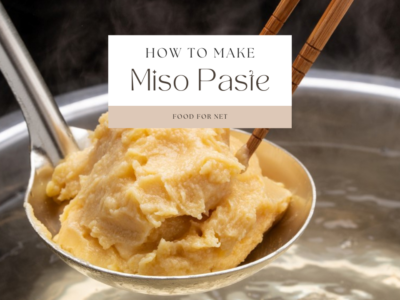 A metal spoon of miso paste being held above an almost boiling pot of water. A pair of chopsticks is also inserted into the miso paste, looking at how to make miso paste.