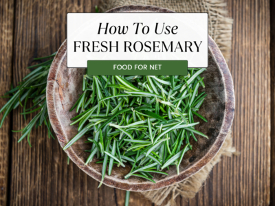A wooden plate with fresh rosemary leaves, looking at how to use fresh rosemary and the impact it has on food