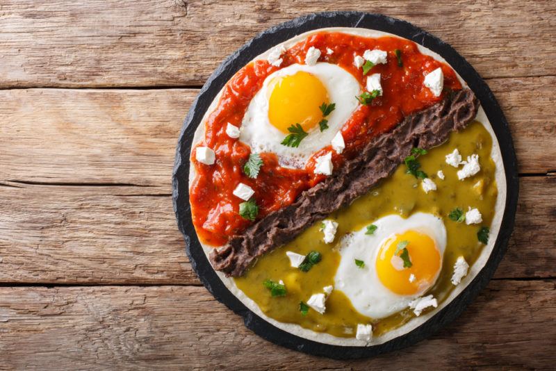 Huevos Divorciados in a pan where one side involves a red sauce, one side involves green sauce and the two are sperated by a wall of refried beans