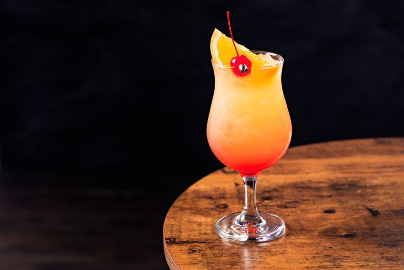 A hurricane cocktail in a tall glass, isolated against a black background