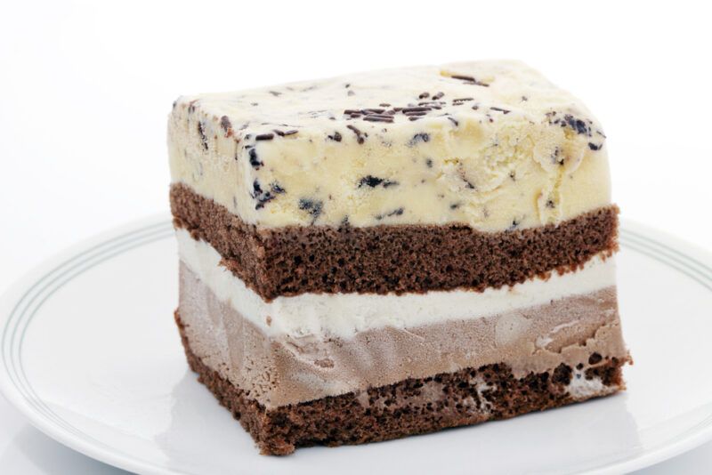 a closeup image of a slice of ice cream cake on a white ceramic dish