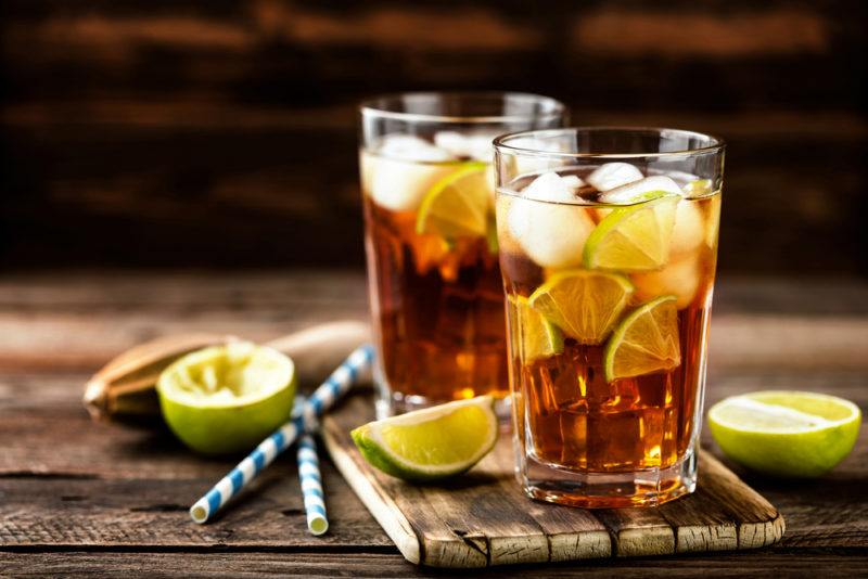 Two glasses of iced tea, with straws and limes on a table