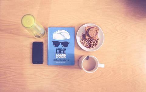 A table with food, coffee, a book and a phone