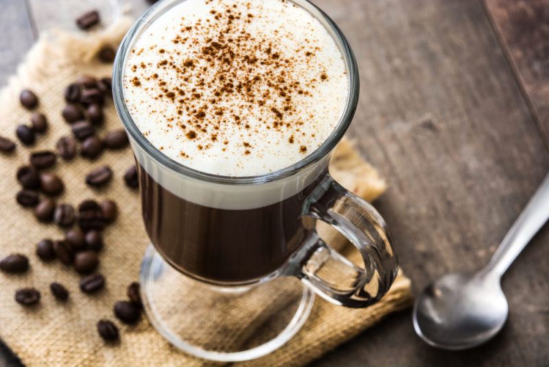 A glass of Irish Coffee with coffee beans on the table