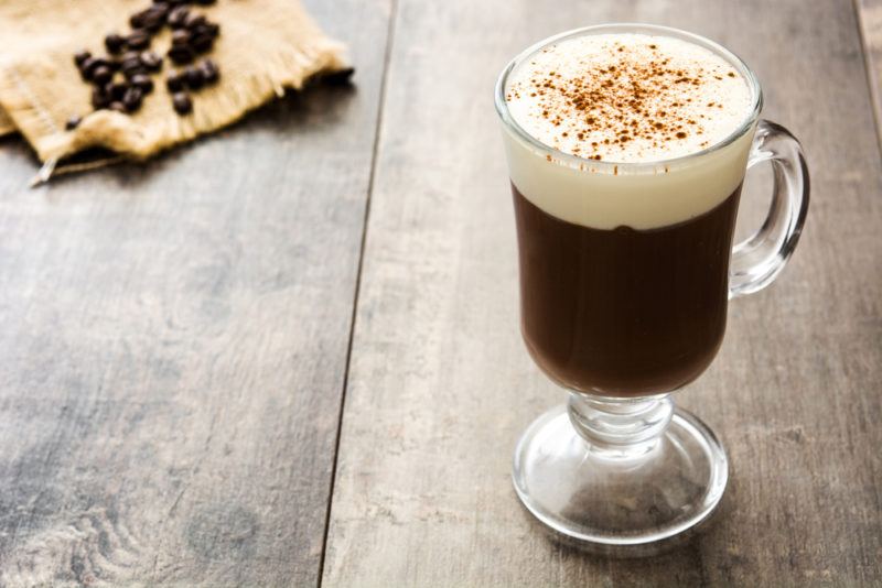 An Irish coffee with a frothy head on a wooden table