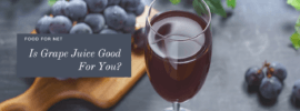 A glass of grape juice next to a wooden board and a bunch of fresh grapes on a table