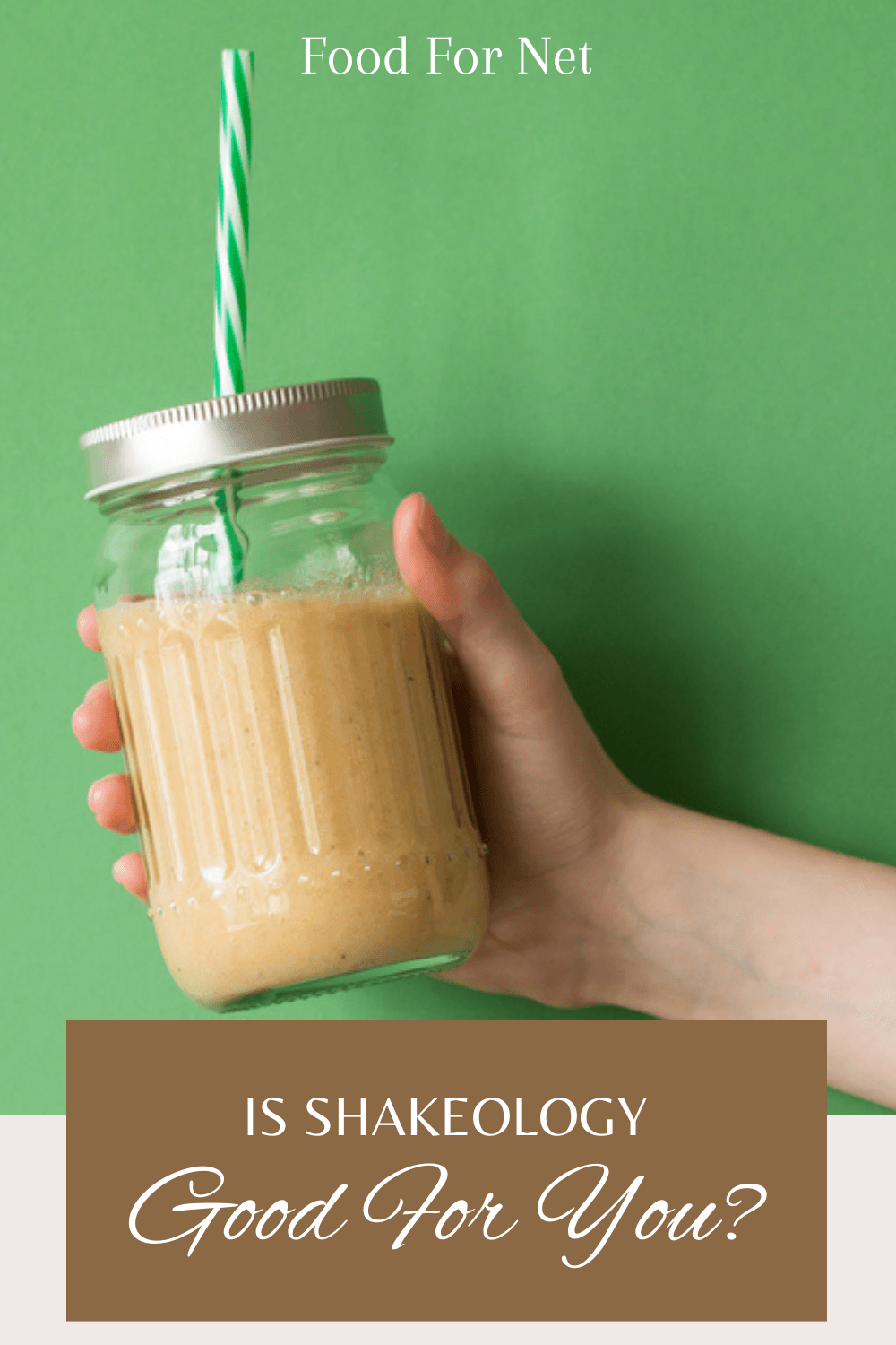 Someone holding up a shake in a mason jar against a light green background, looking at whether Shakeology is good for you