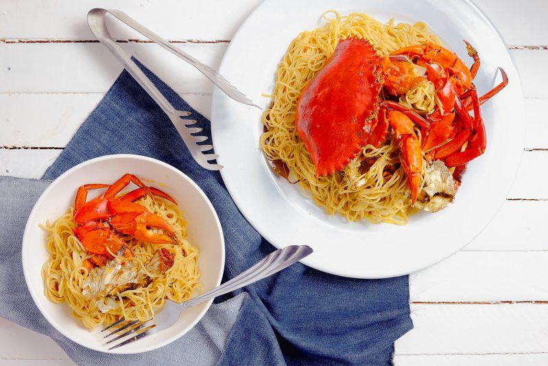 crab shells and crab meat on angel hair pasta noodles with white background