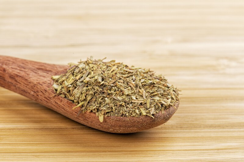 a wooden surface with a wooden ladle full of Italian seasoning