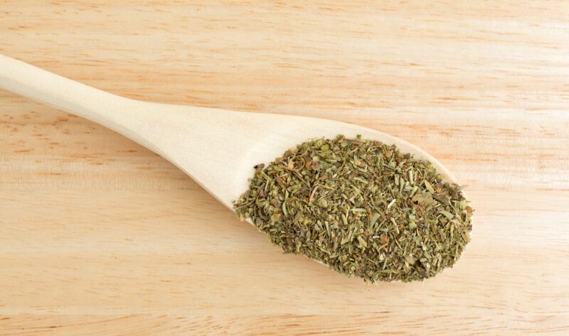 an overhead shot of a wooden spoon full of Italian seasoning on a wooden surface