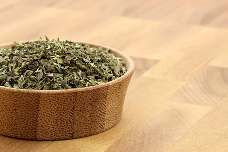 on a wooden surface is a closeup image of a wooden container full of Italian seasoning