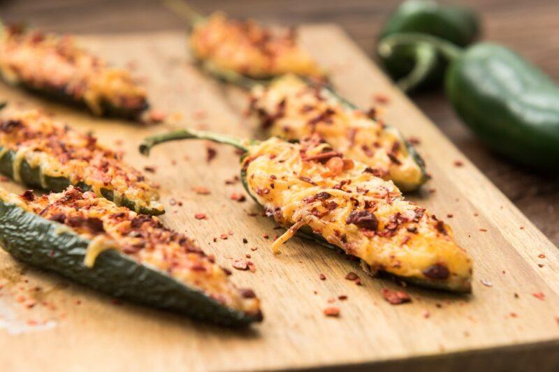 A wooden board with jalapeno poppers