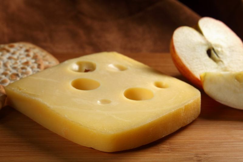 Jarlsberg cheese with an apple on a table