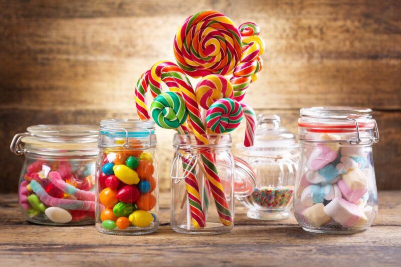 Various jars containing sweet treats, including marshmallows, gummy worms, lollipops, and sprinkles.