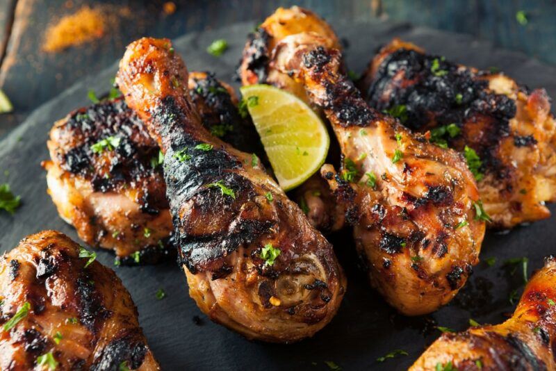 A black plate with a variety of jerk chicken drumsticks