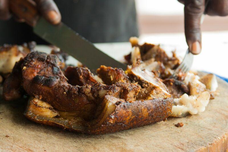 A man preparing jerk pork on a wooden board