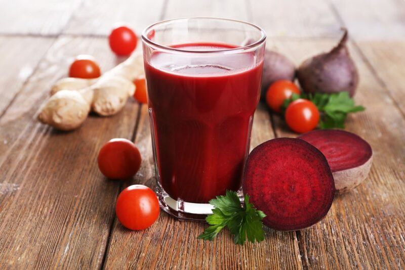 A glass of beet juice that also uses cherry tomatoes and ginger