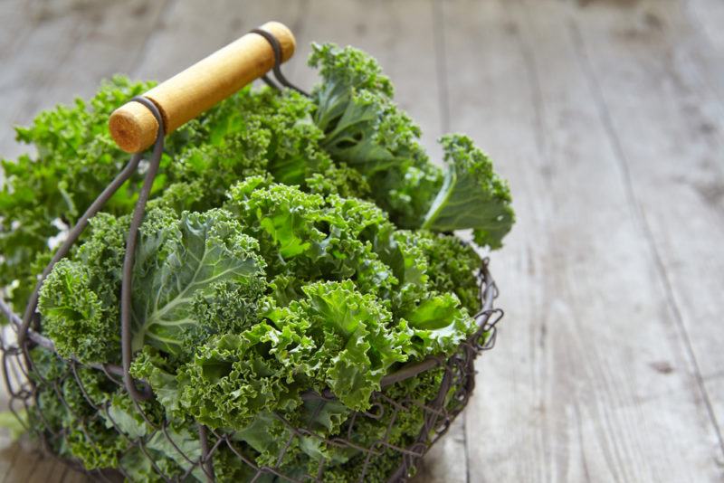 A basket with a handle containing curly kale